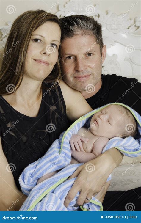 Caucasian couple wearing black suits hold their infant son. Loving .